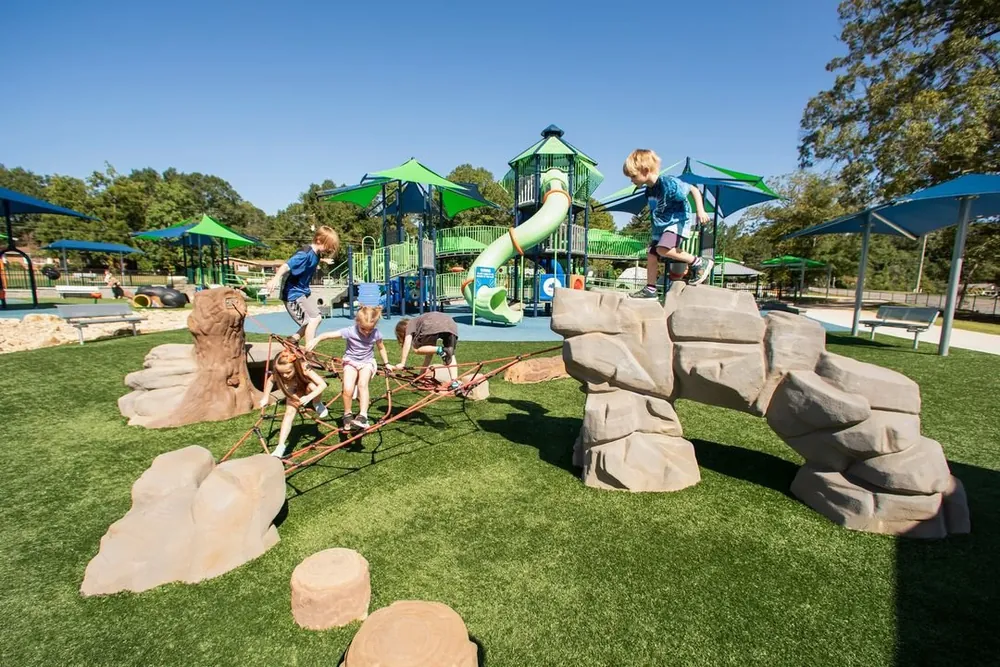 Children using a wheelchair-accessible roundabout on blue surfacing